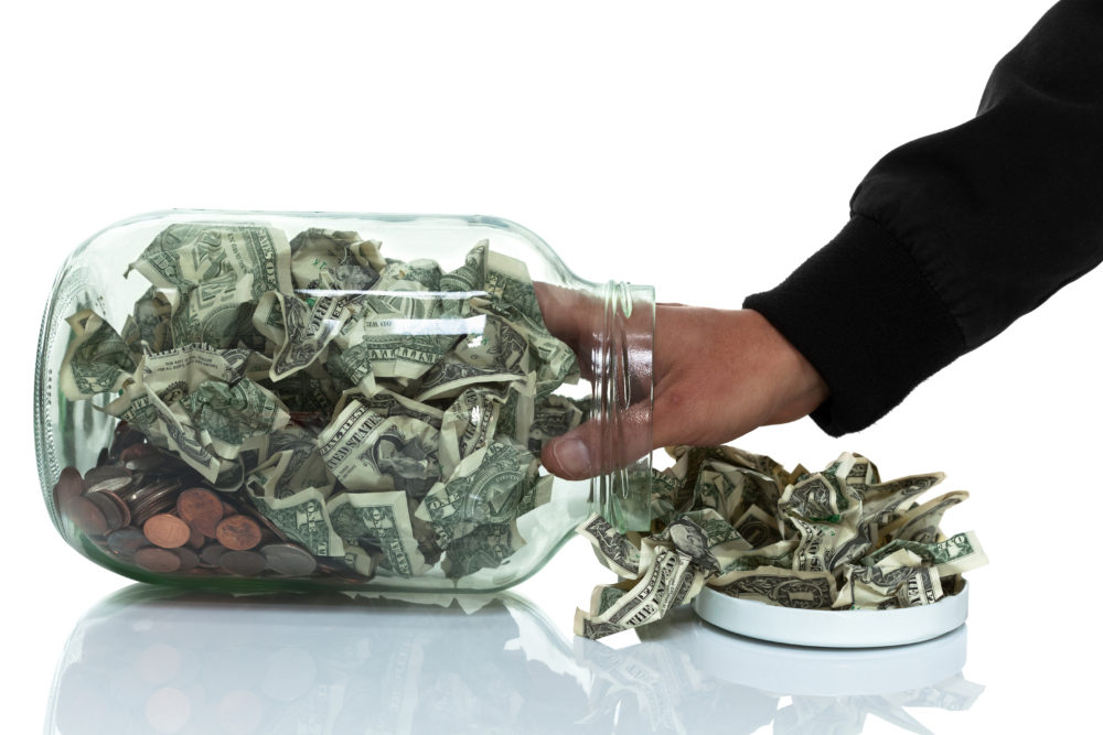 Hand reaches into jar for money.
